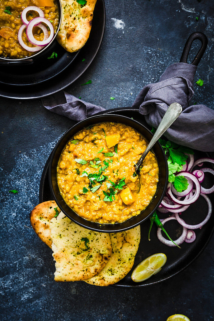 Indian Dahl served with Naan bread, onion rings, lemon wedge and coriander leaves