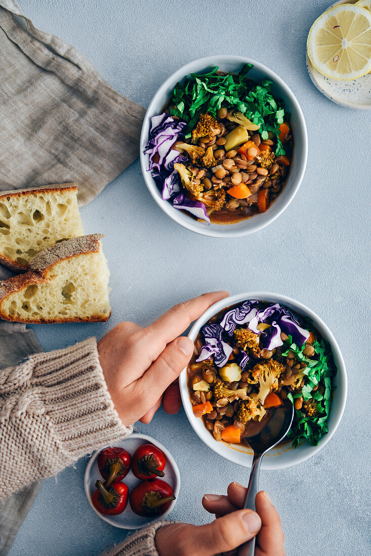 Vegan lentil stew with broccoli and carrot garnished with shredded red cabbage and chopped parsley