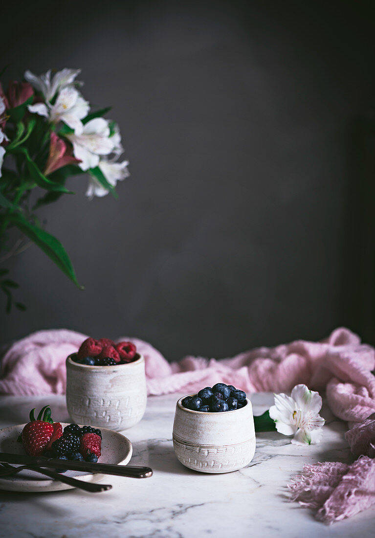 Raspberries and blueberries on glasses on table