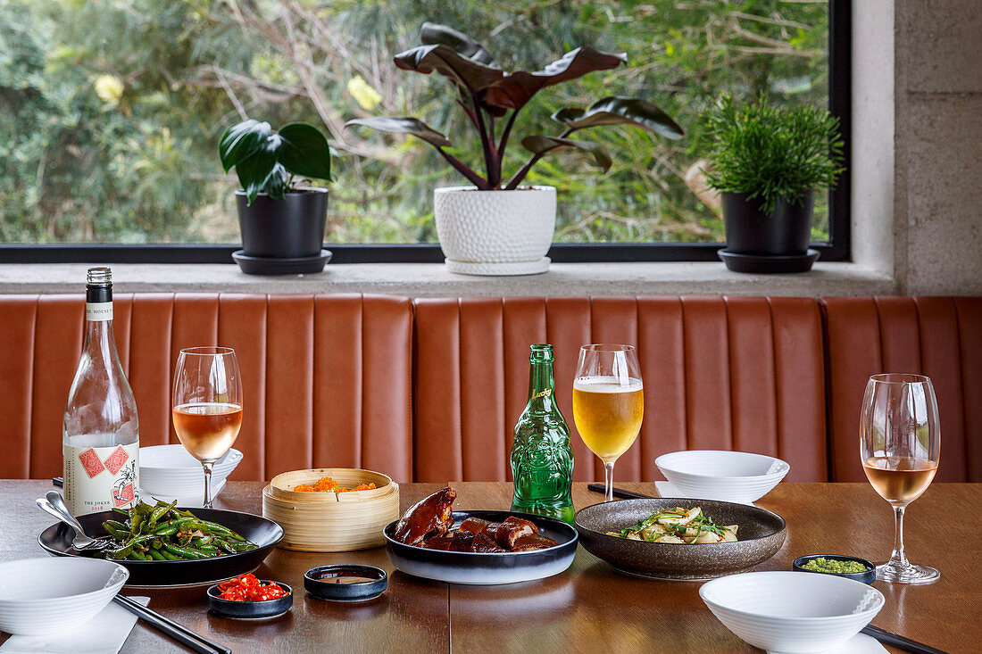 Gedeckter Tisch mit asiatischen Speisen, Wein und Bier