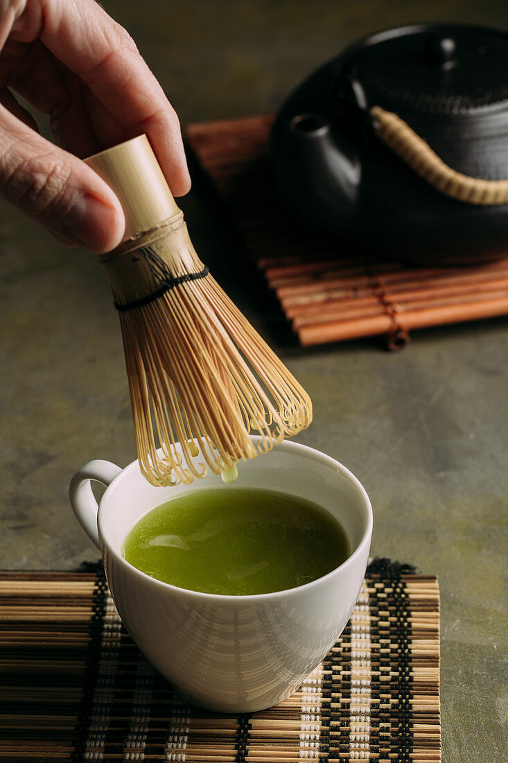 Preparing matcha tea with bamboo whisk