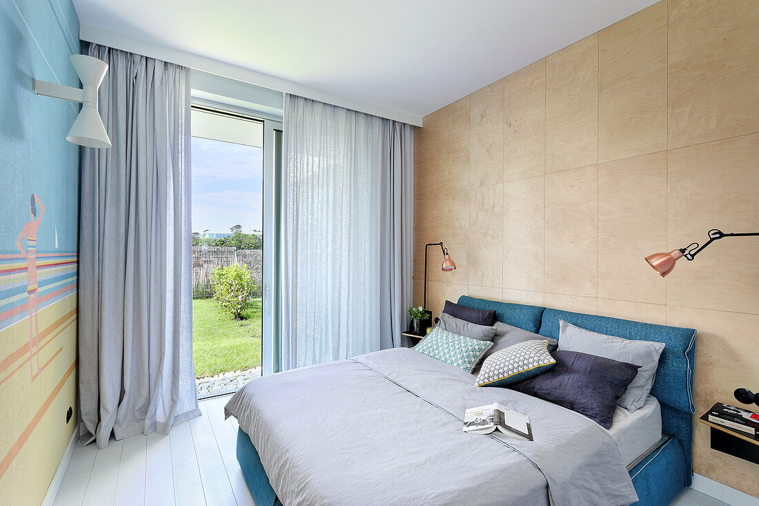 Wall clad in plywood panels in summery bedroom