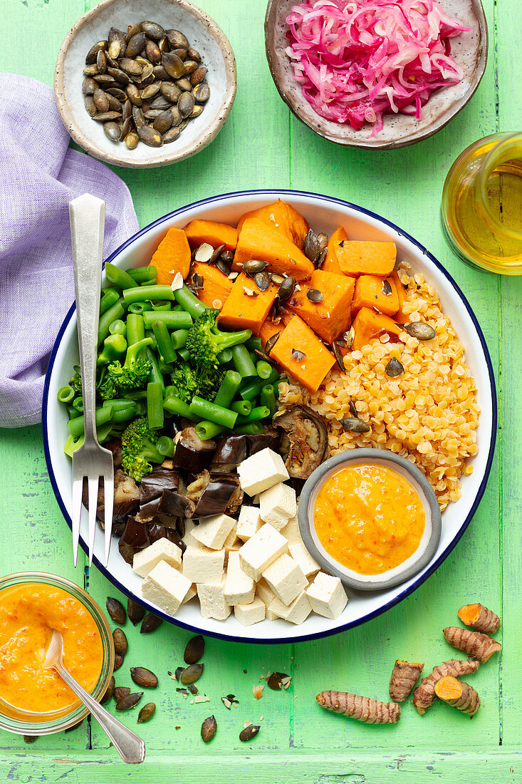 Buddha bowl (vegan) with red lentils, sweet potatoes, tofu, eggplant and greens, ajvar