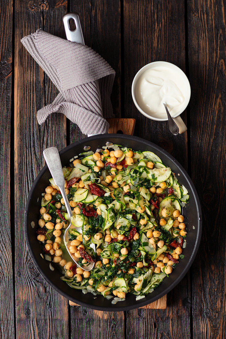 Chickpeas, spinach, courgette and dried tomatoes on a pan