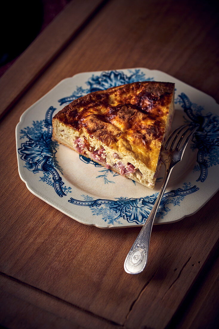 A piece of bacon quiche on a vintage plate