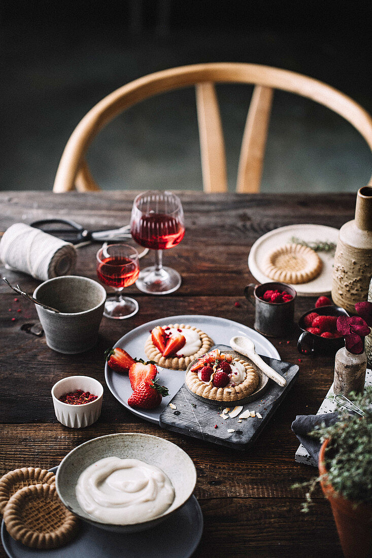 Cake tartlets with vanilla pudding and strawberries on a rustic table