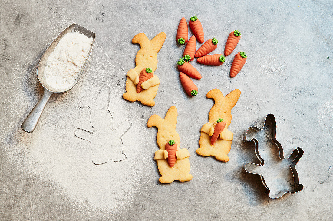 Easter Bunny biscuits with marzipan carrots, cookie cutter and a scoop with flour