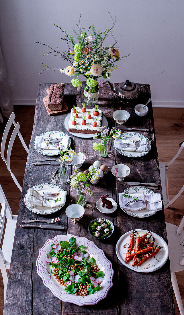 Gedeckter Ostertisch mit Frühlingssalat, Ofenmöhren und Möhrenkuchen