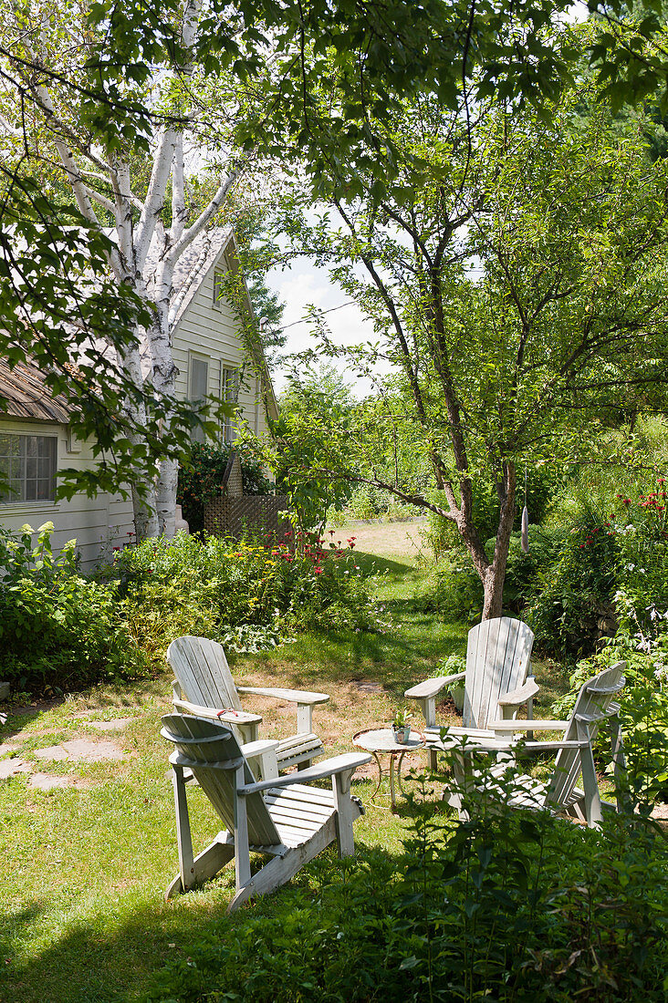 Deckchairs and table on lawn in summery garden