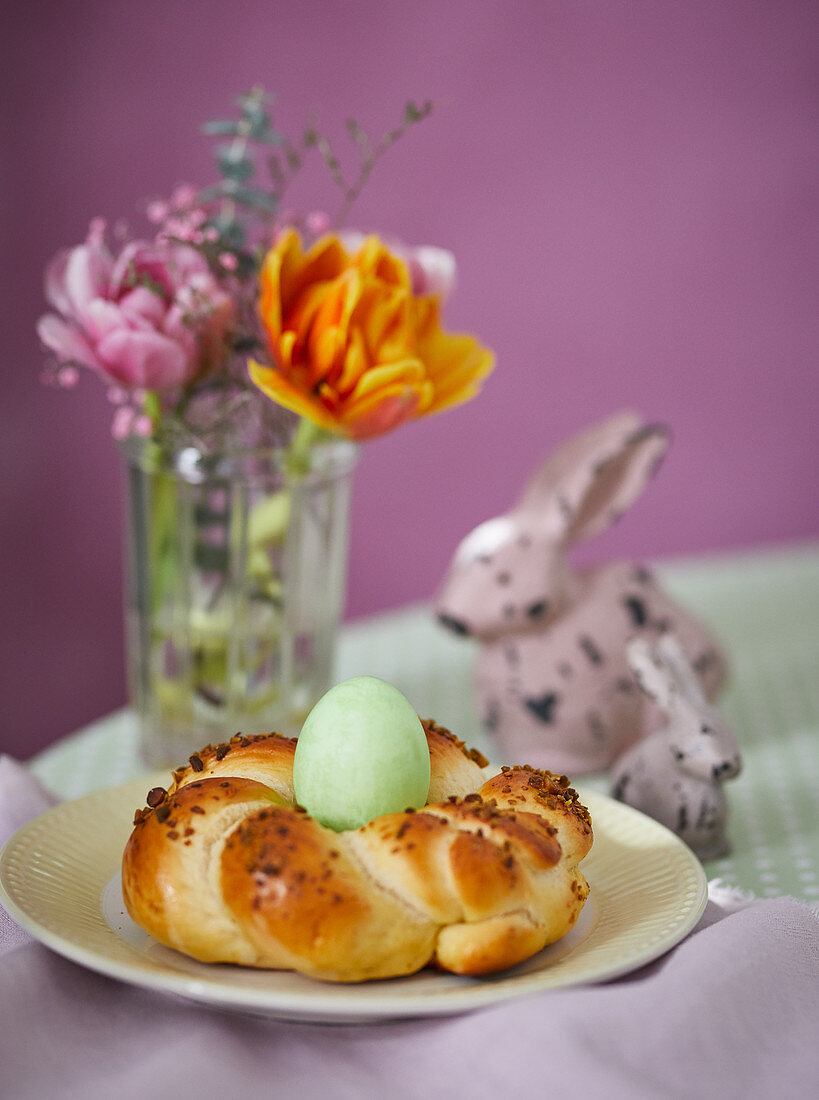 A coloured Easter egg in a bread wreath nest on an Easter table