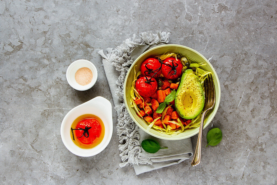Delicious vegan dinner bowl. Fresh salad, avocado half, grains, beans, roasted vegetables