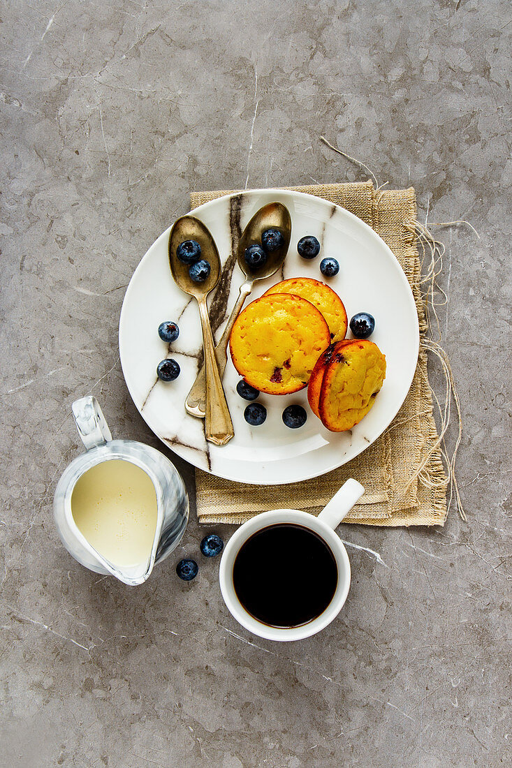 Blaubeermuffins, frische Blaubeeren, Kaffee und Milch