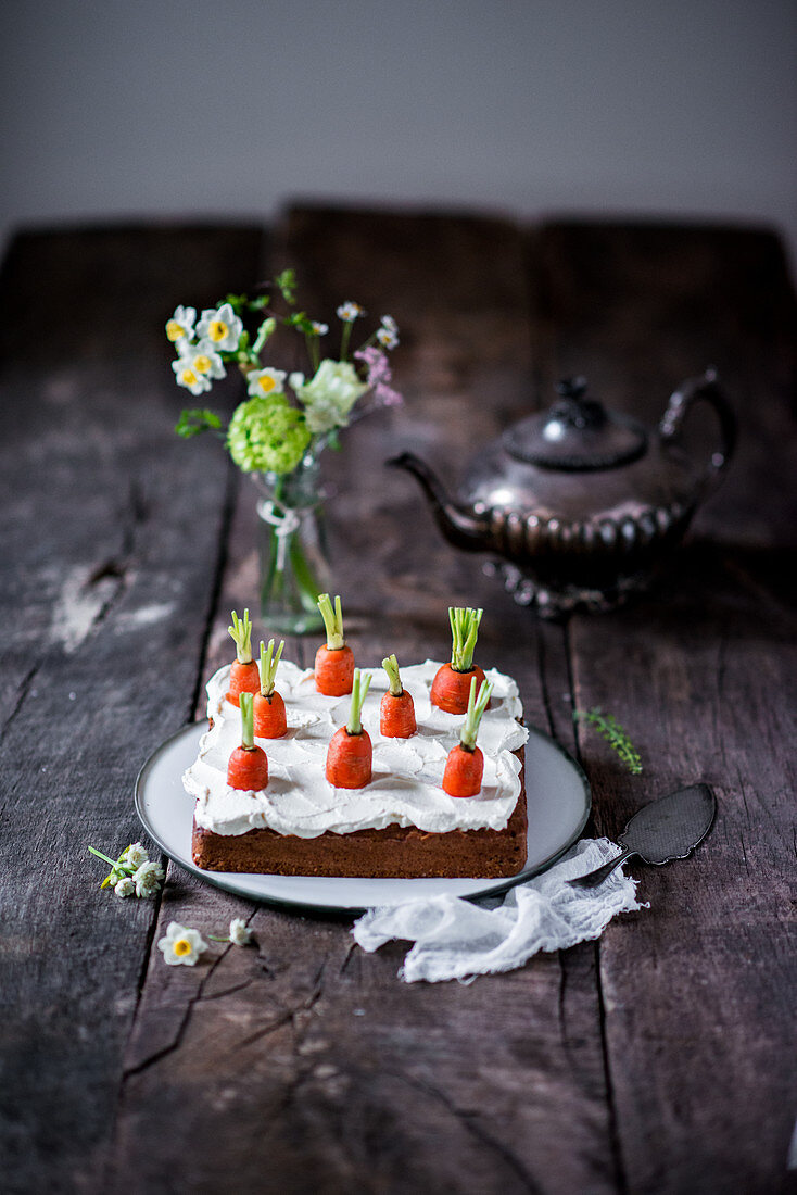 Möhrenkuchen mit Frischkäsetoppin, Frühlingsblumen und Teekanne