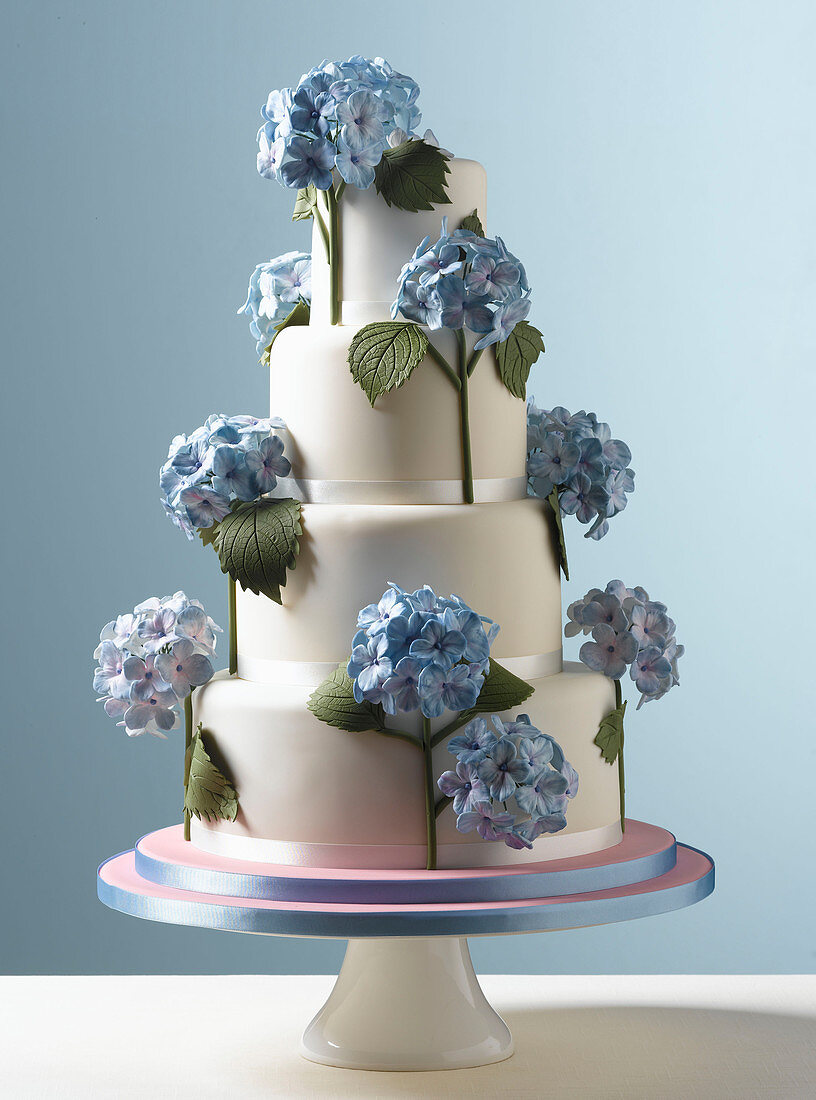 Easter Celebrations, tiered white wedding cake with blue hydrangea flowers with a pale blue background