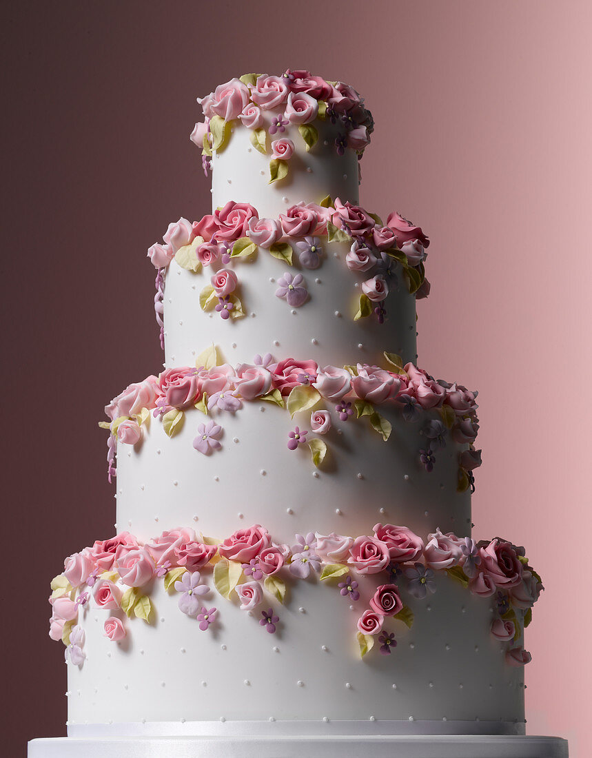 Vierstöckige, weiße Hochzeitstorte mit gezuckerten Rosenblüten