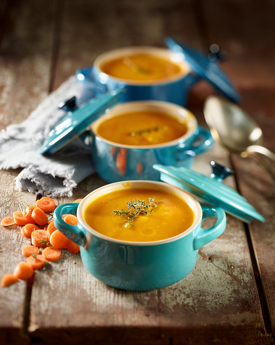Karotten-Orangen-Suppe in drei kleinen Suppentöpfen serviert