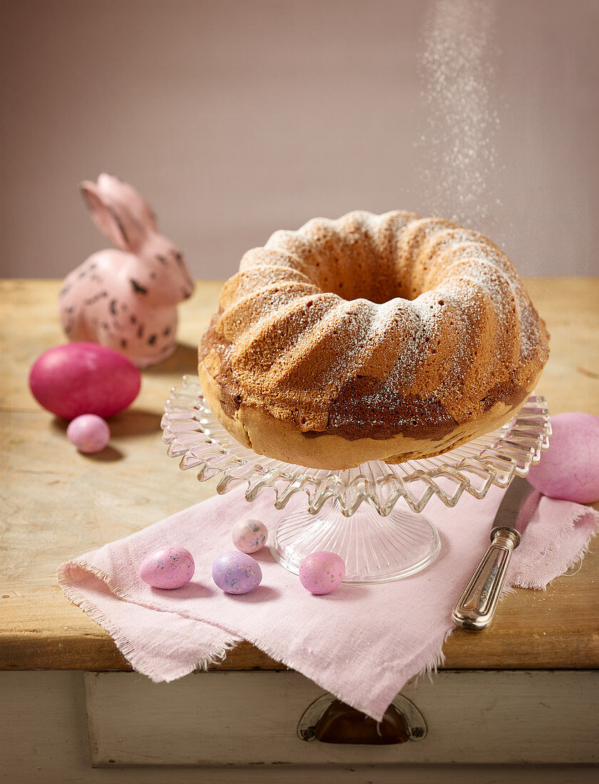 A marble Bundt cake dusted with icing sugar with Easter decorations