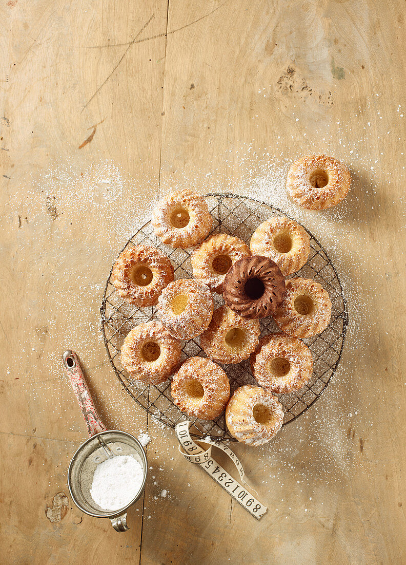 Mini Bundt cakes on a round wire rack dusted with icing sugar