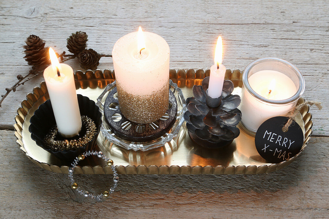 Four burning candles with Christmas decorations on a tray