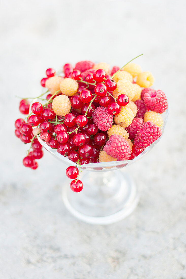 Raspberries, golden raspberries and redcurrants in a footed crystal bowl