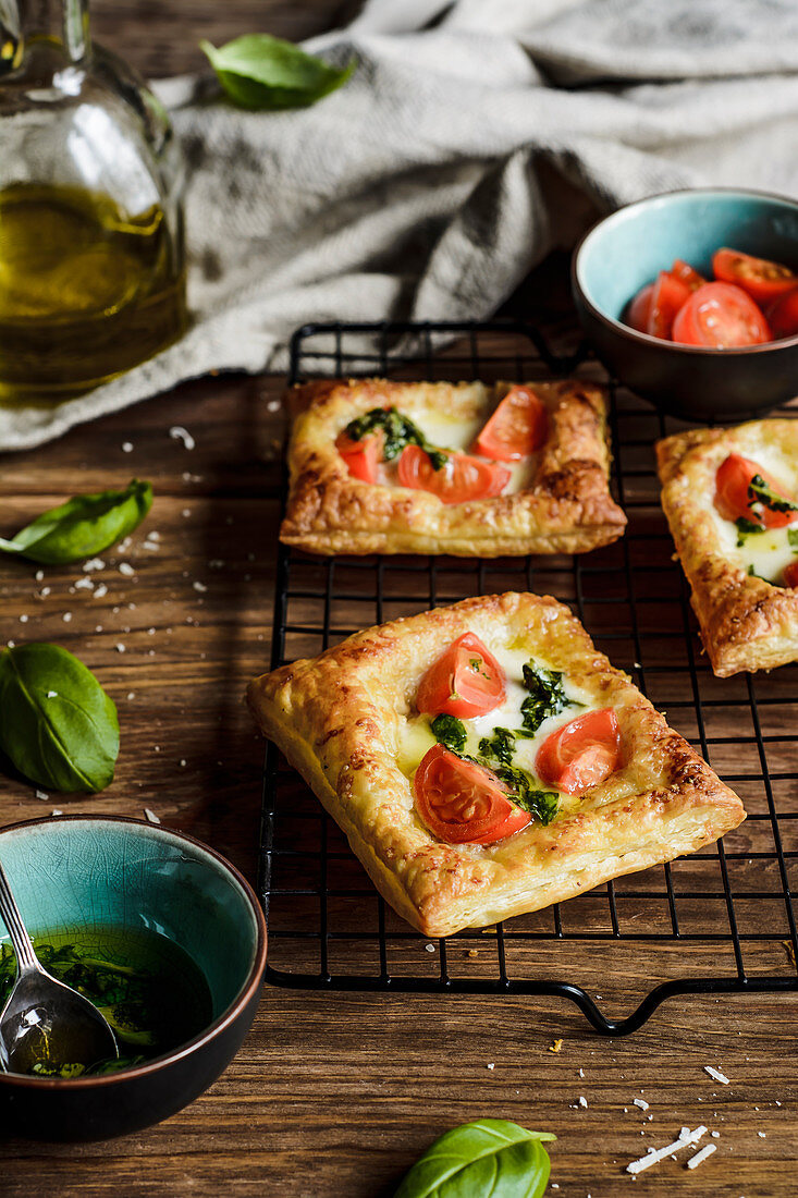 Puff pastries topped with mozzarella, cherry tomatoes and basil oil