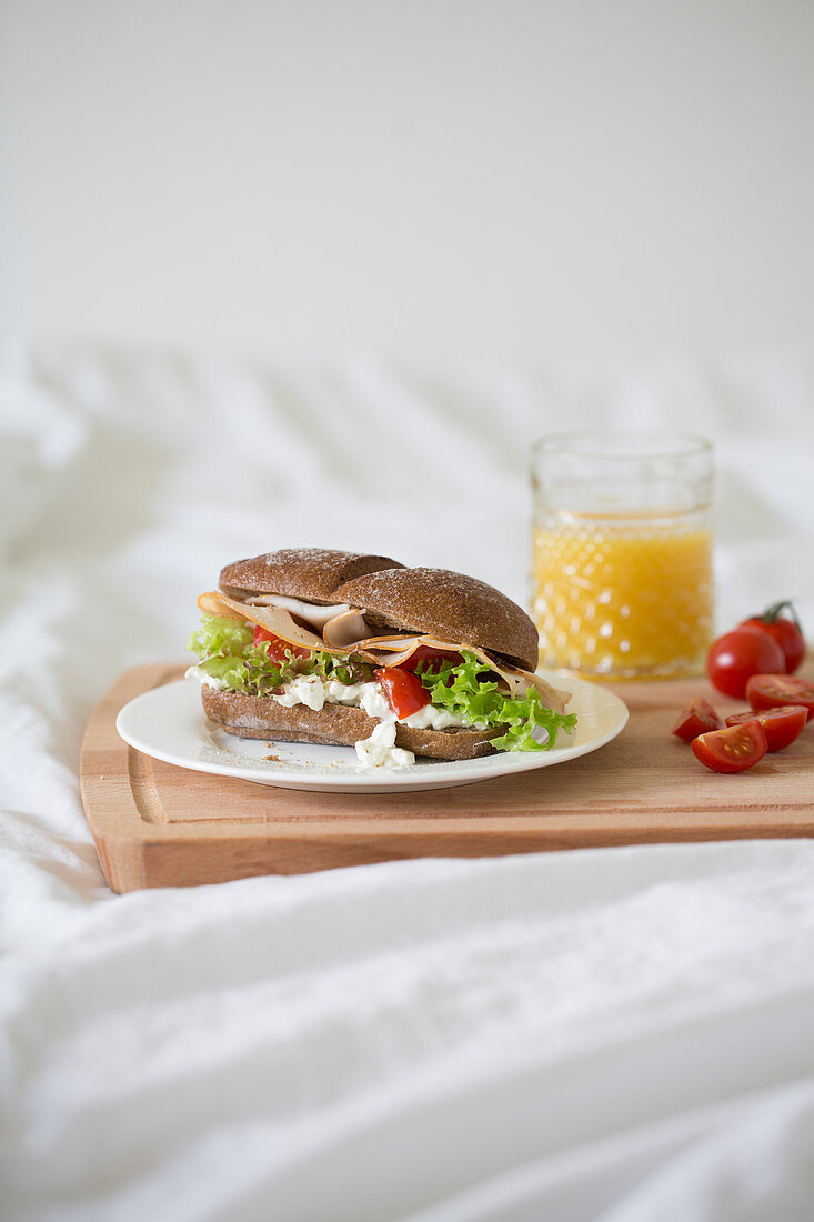 Breakfast in bed with a rye bread roll and orange juice