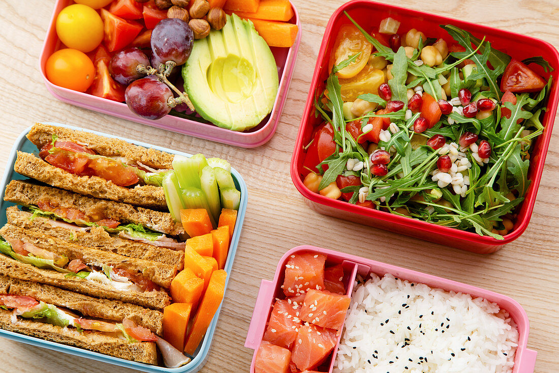 Creative layout with healthy lunch dishes variety in bento boxes on wooden table