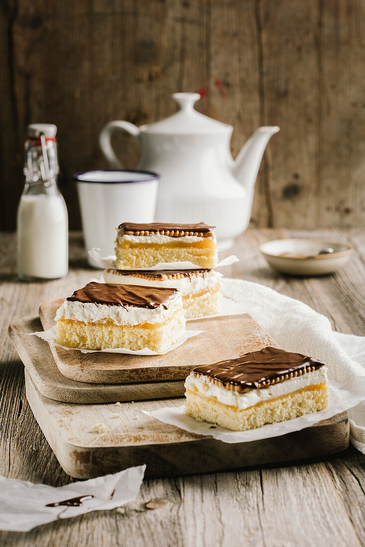 Slices of biscuit cake with chocolate glaze on a wooden board