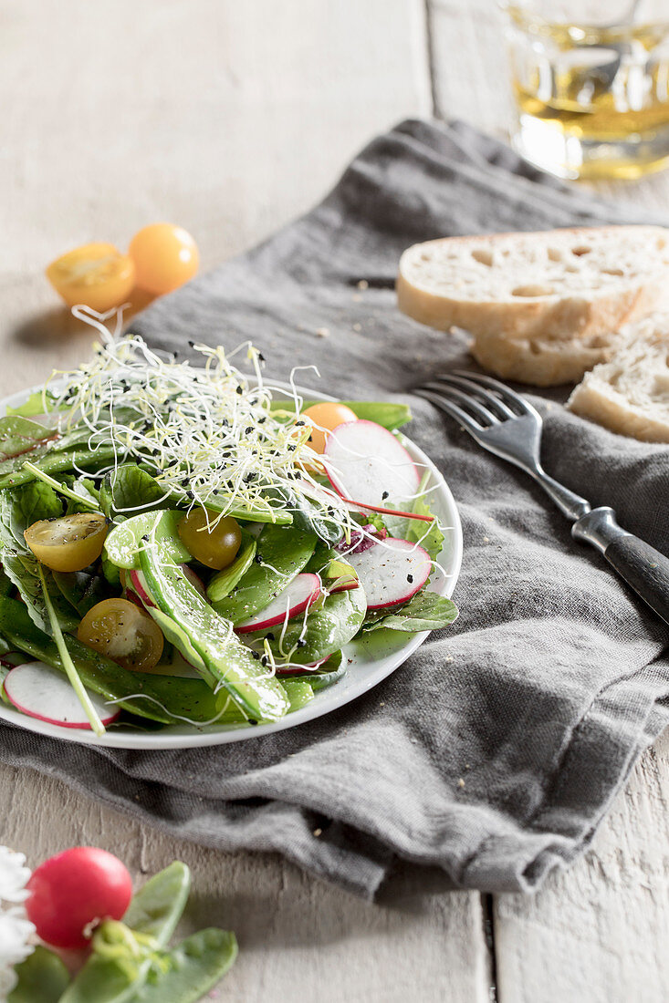 Mange tout salad with beansprouts, radishes and yellow tomatoes