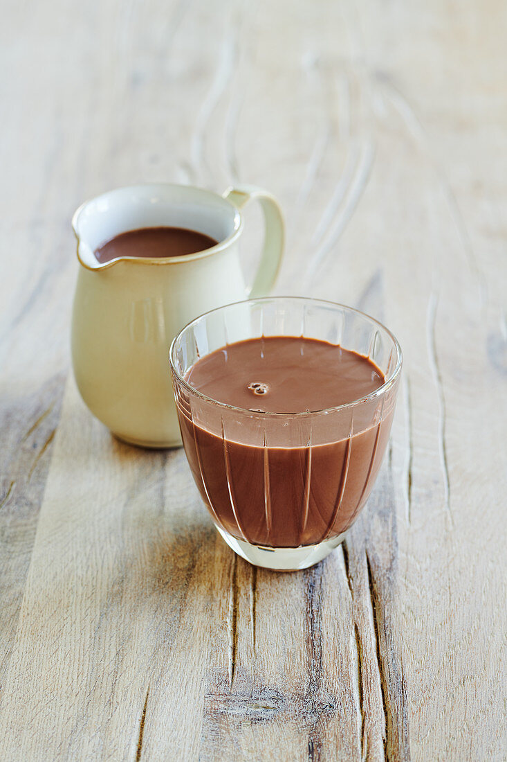 Schokoladenmilch im Glas und Kännchen
