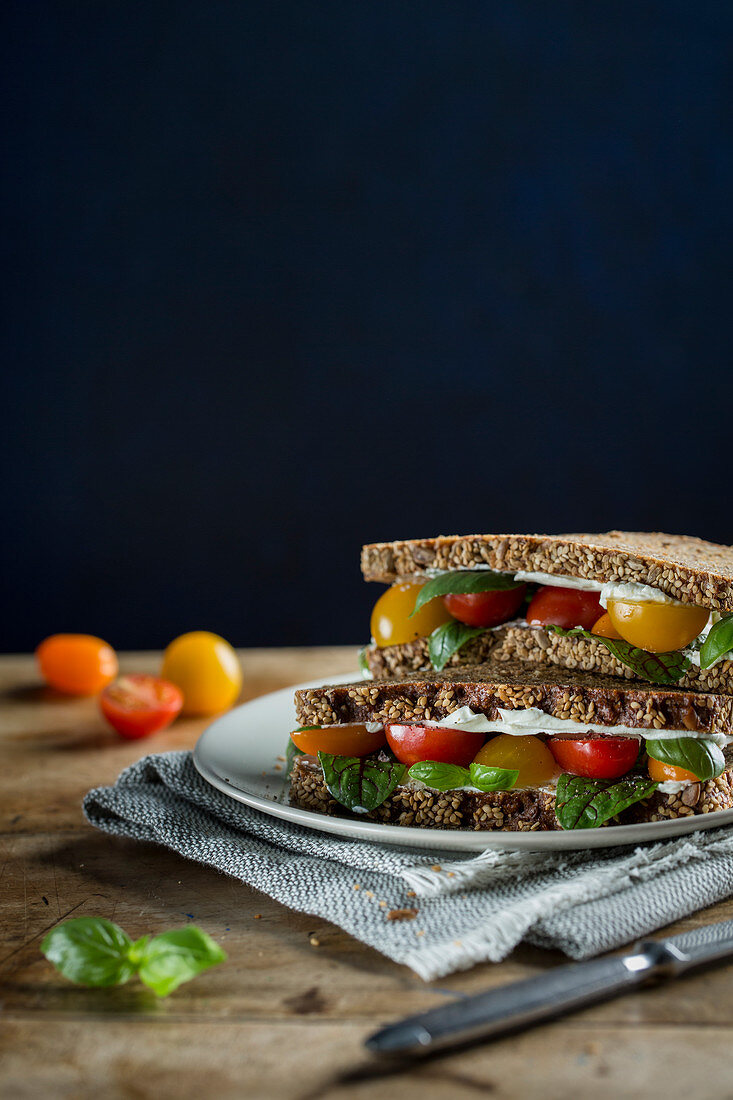 Vollkornbrotsandwiches mit Frischkäse, Kirschtomaten und Basilikum