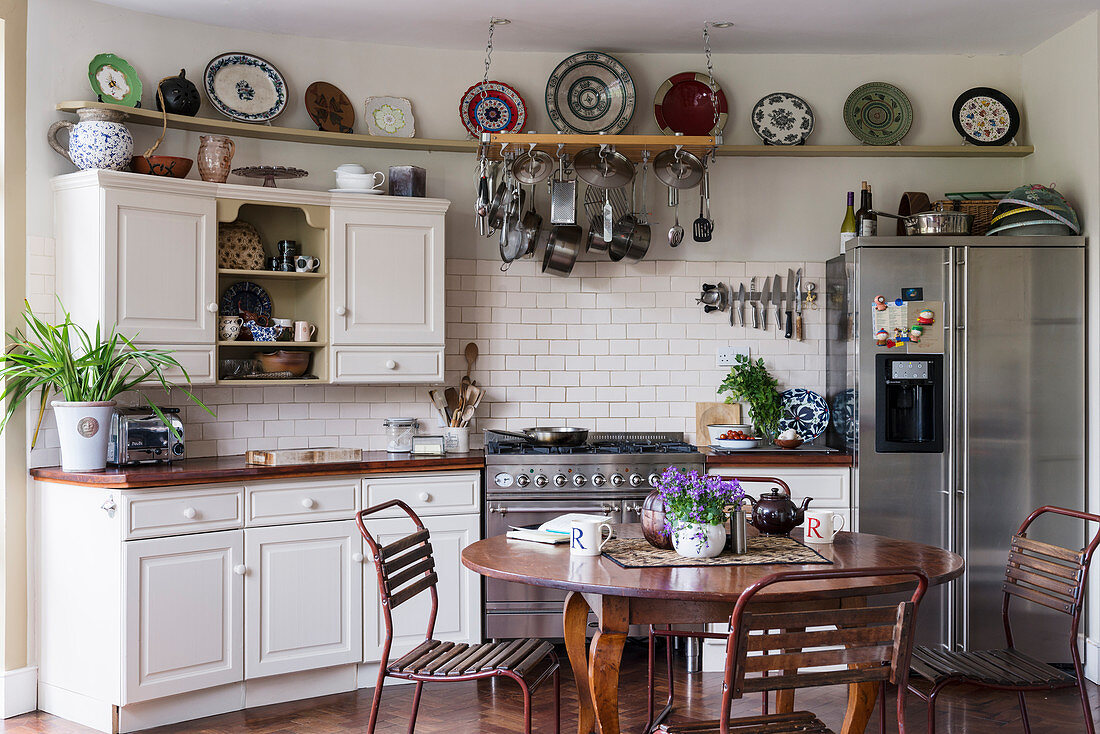 Metal chairs around wooden table in country-house kitchen with curved wall