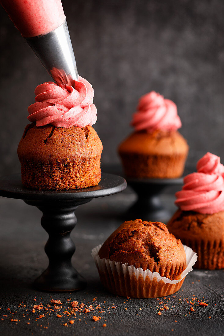 Muffins mit rosa Fruchttopping bespritzen