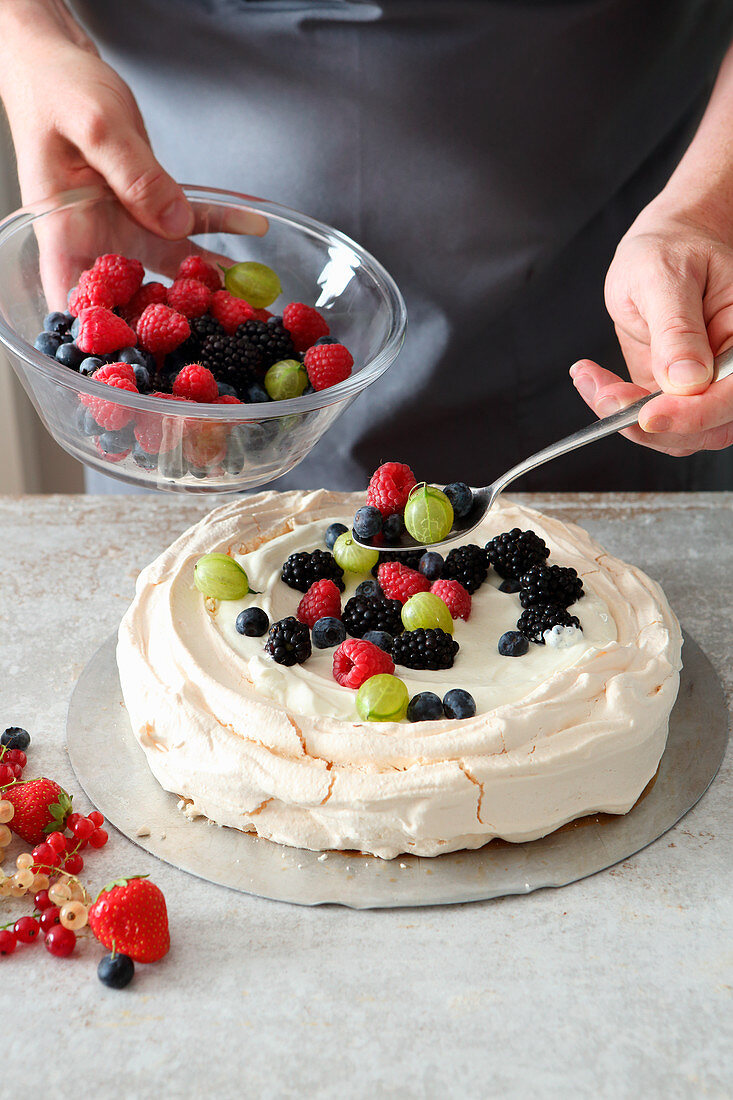 Berries being added to pavlova