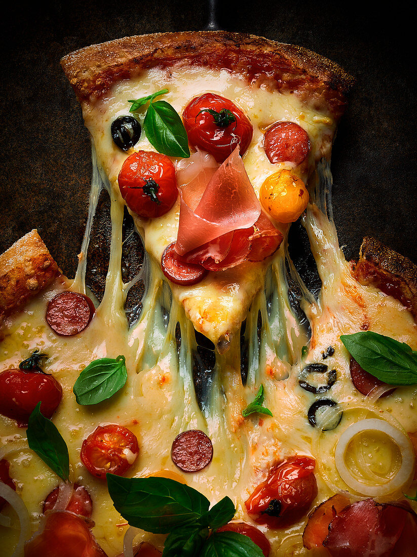 Pizza mit Salami, Schinken, Tomaten, Oliven und Käse