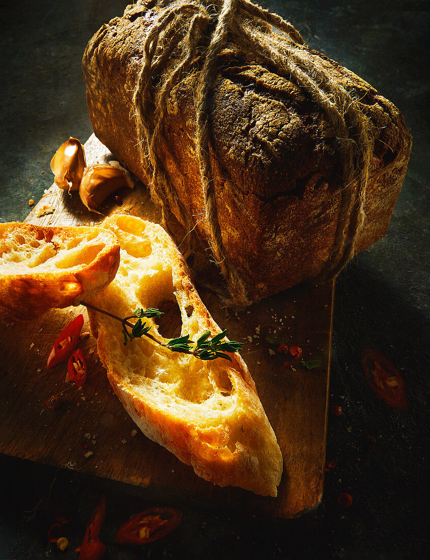 Ciabatta slices and a rustic loaf of bread on a wooden board