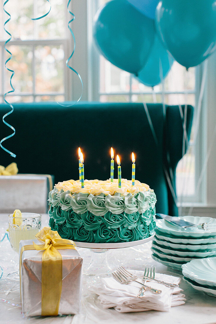 Türkiser Geburtstagskuchen mit brennenden Kerzen