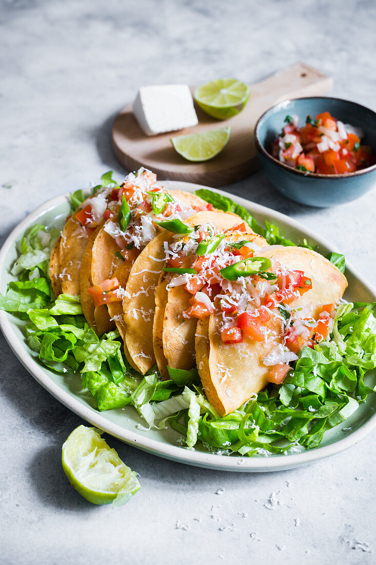 Tacos de papa (with potato filling) on salad with tomato salsa