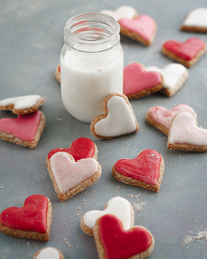 Pink, red and white heart-shaped biscuits with a glass of milk
