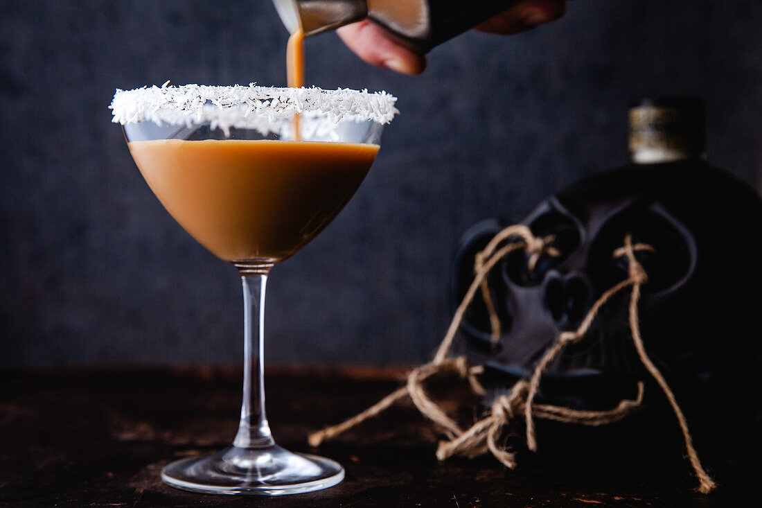 An Easter cocktail with eggnog, rum, espresso, with coconut flakes on the rim of the glass