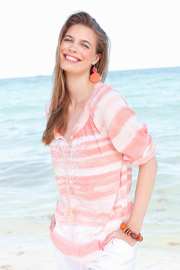 A young woman by the sea wearing a striped blouse
