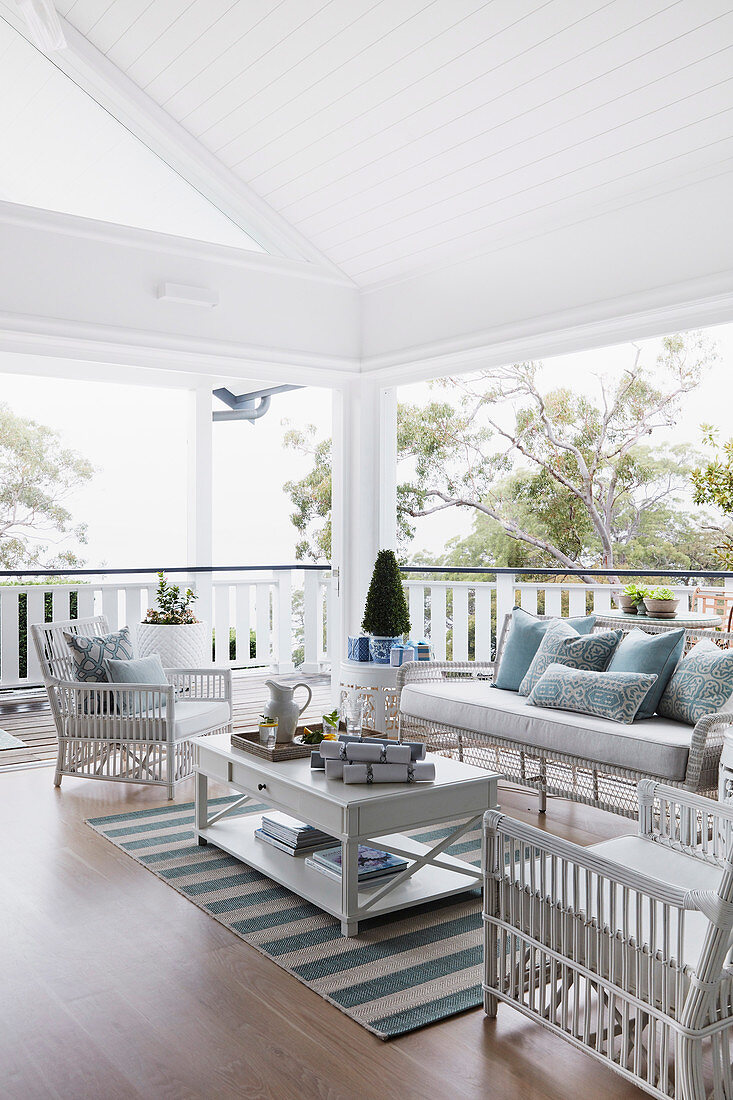 White wicker furniture with light blue decorative pillows on a covered veranda