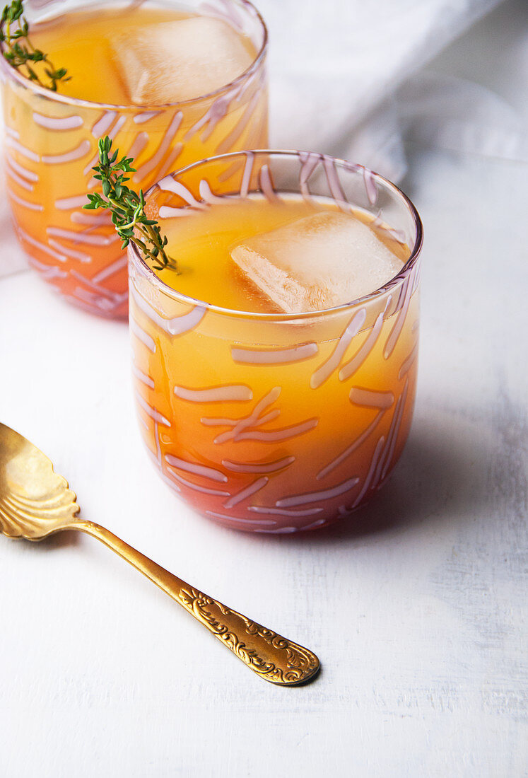 Two glasses of guava rum punch with herb garnish