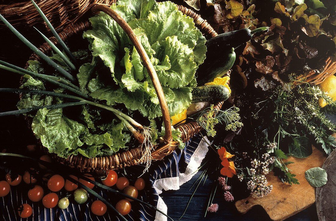 Eissalat & Gemüse im Korb; daneben Tomaten, Kräutern, Salat