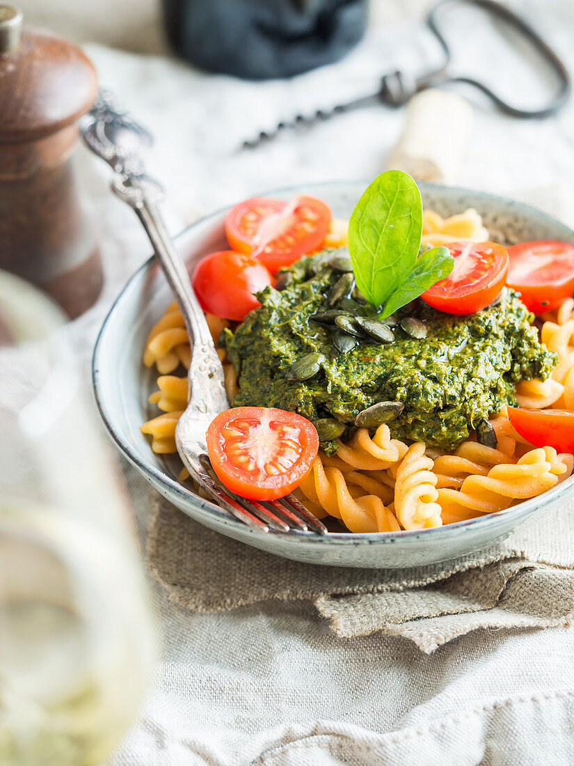 Vegan green pesto with dried tomatoes, seved with gluten-free red lentil fussili pasta