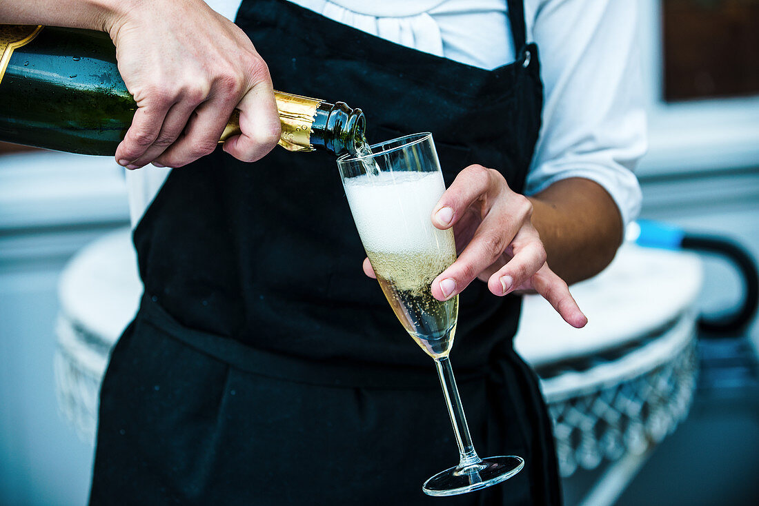 A waiter pouring champagne into a glass