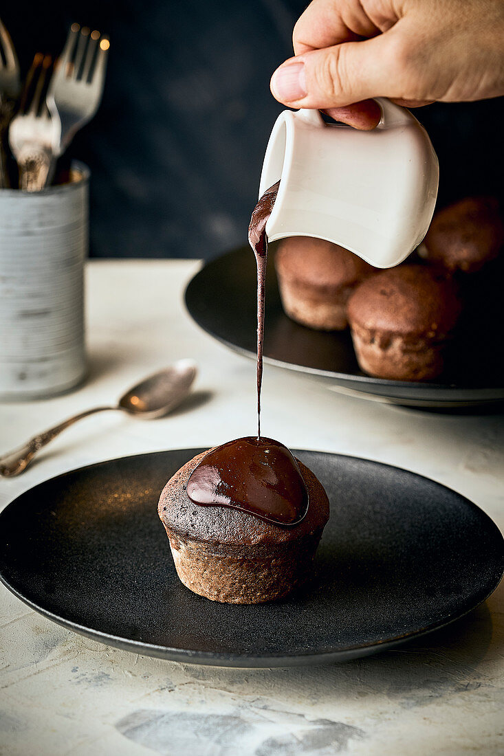 Muffin mit Schokoladensauce begießen