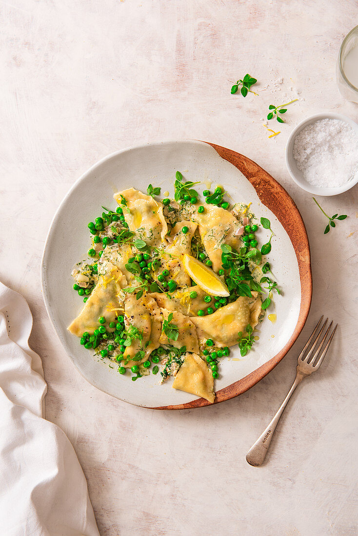 Homemade spinach, ricotta and salmon ravioli with dill butter, peas and lemon