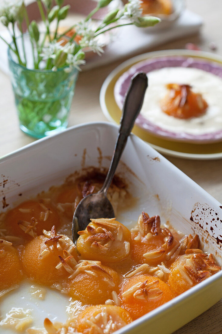 Baked apricots with almonds in a baking dish, served with vanilla ice cream