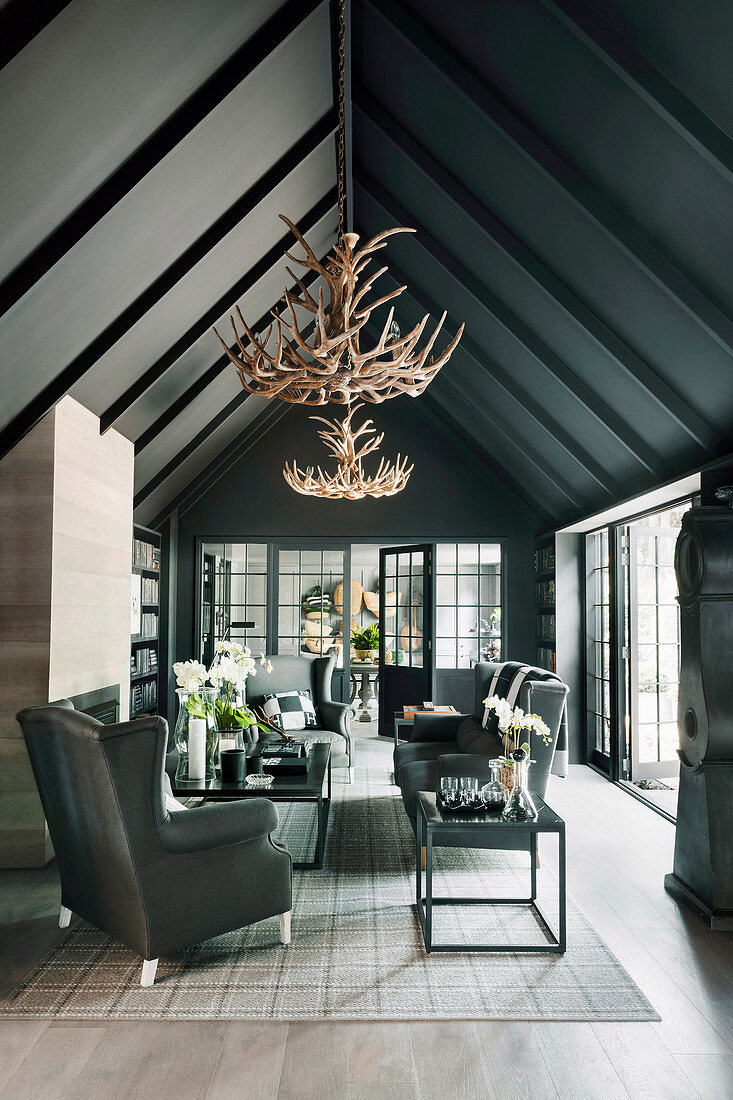 Living room in black under gable roof with impressive antler chandeliers